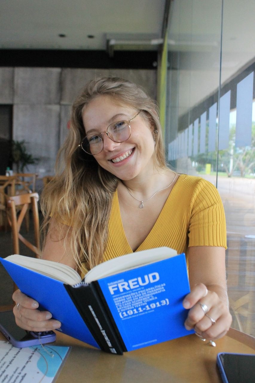 Jennifer Patrícia Kuhn Lago sorrindo com um livro de Freud